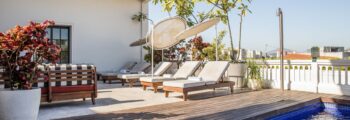 Resort tropical : piscine, transats, pavillon, palmiers.